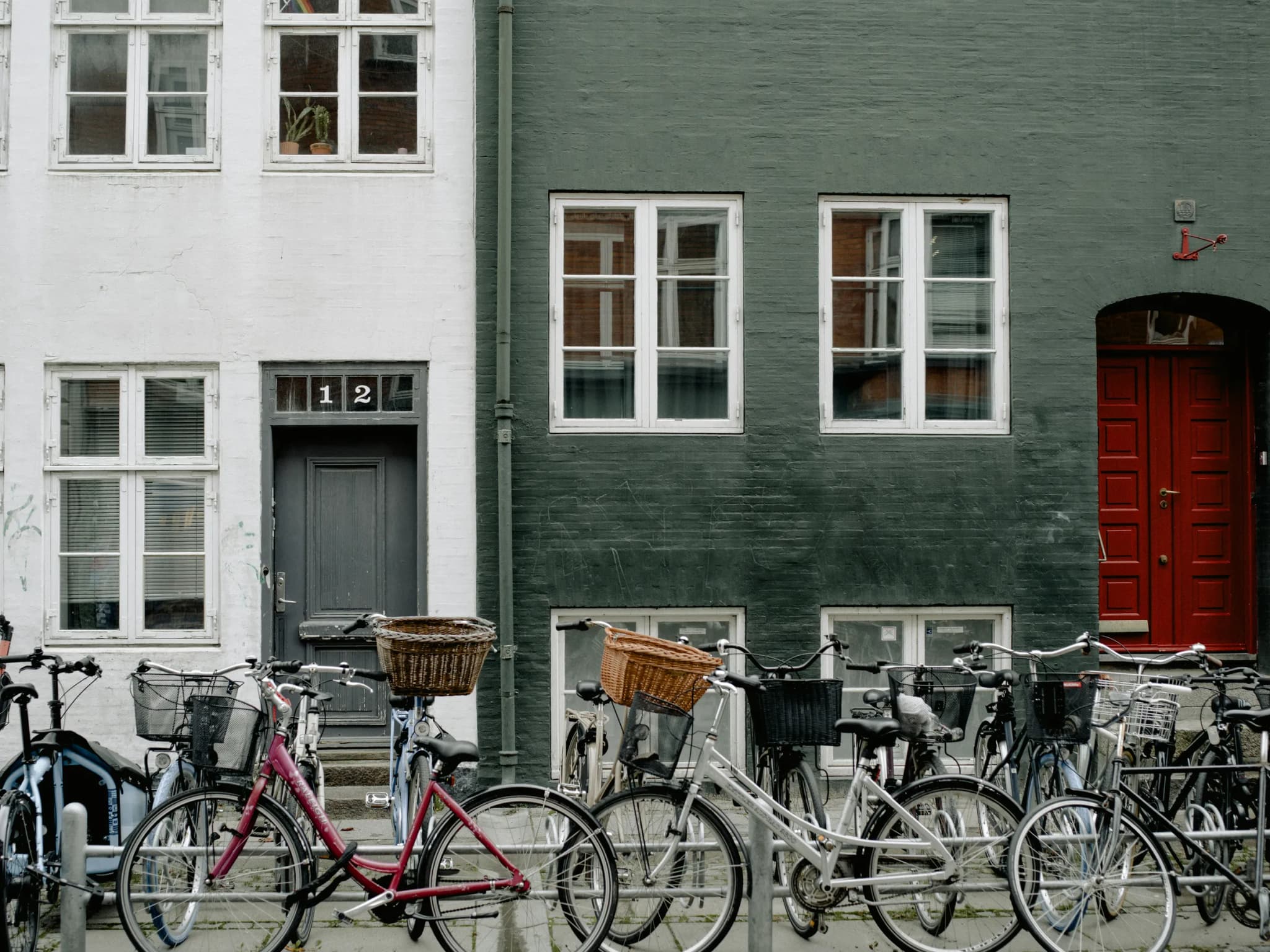 Older apartment buildings with white and dark green facades and bicycles parked outside