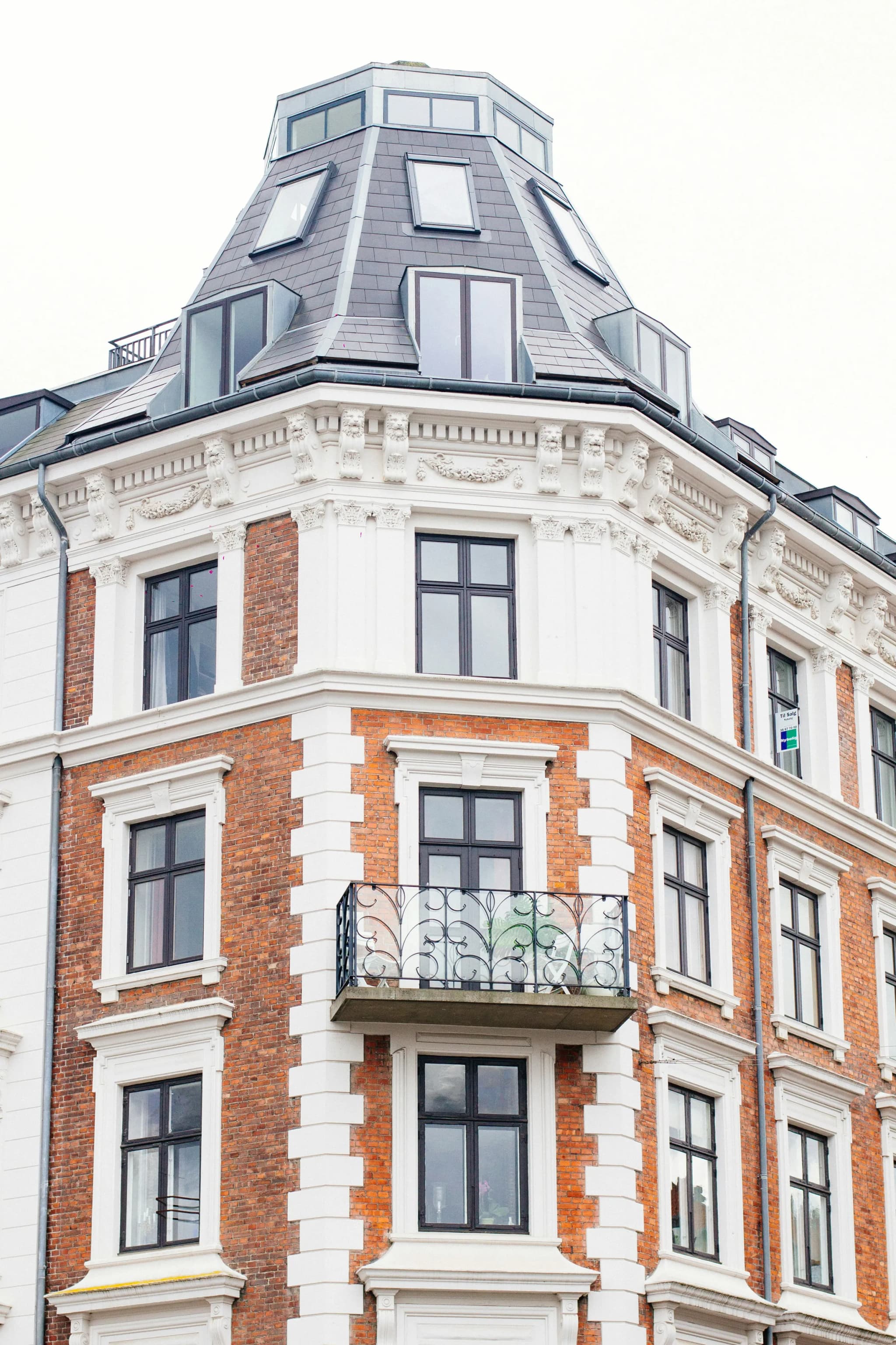 Red-brick corner building with dormers and balconies