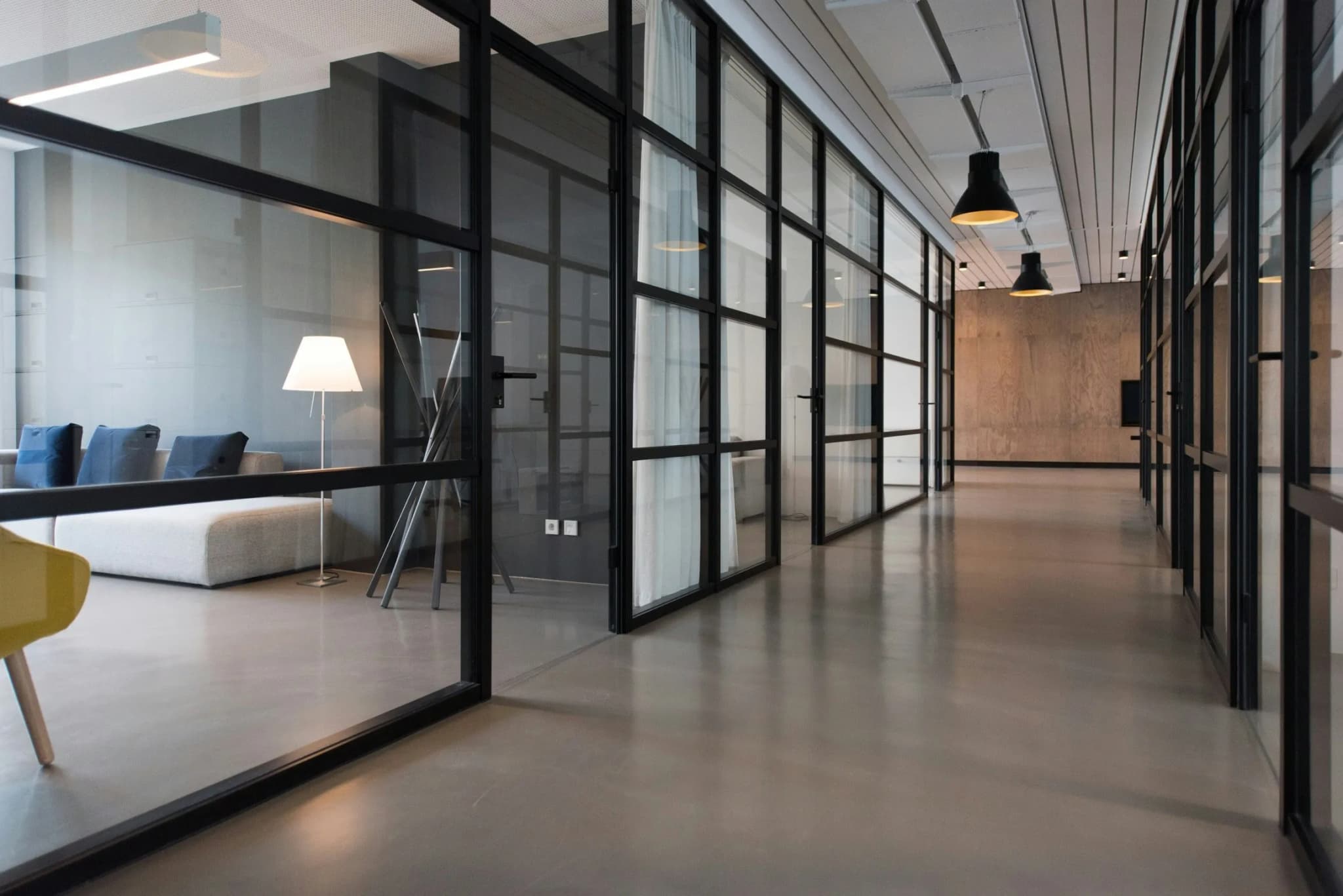 Bright office corridor with glass walls and a concrete floor