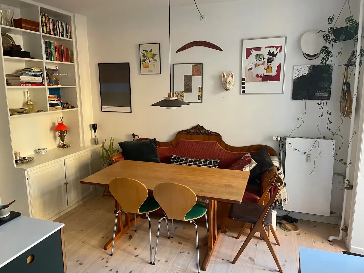 Spisebord foran en rød sofa, med reoler og billeder på væggene