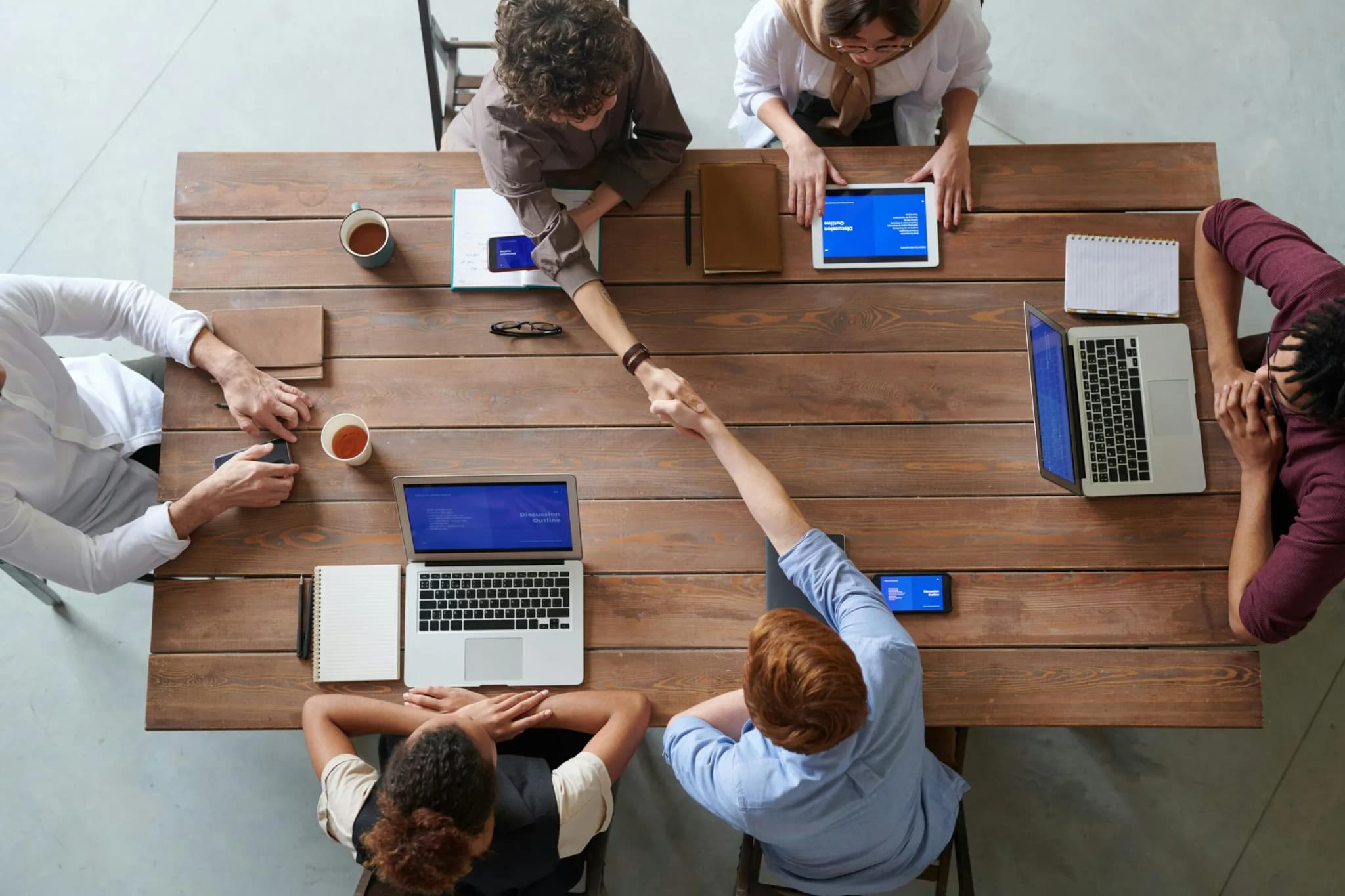 Overhead view of colleagues in a work meeting using laptops and tablets