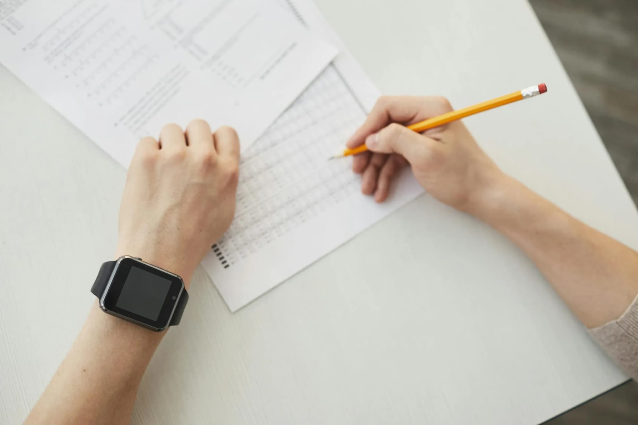 A student writing an exam with a pencil