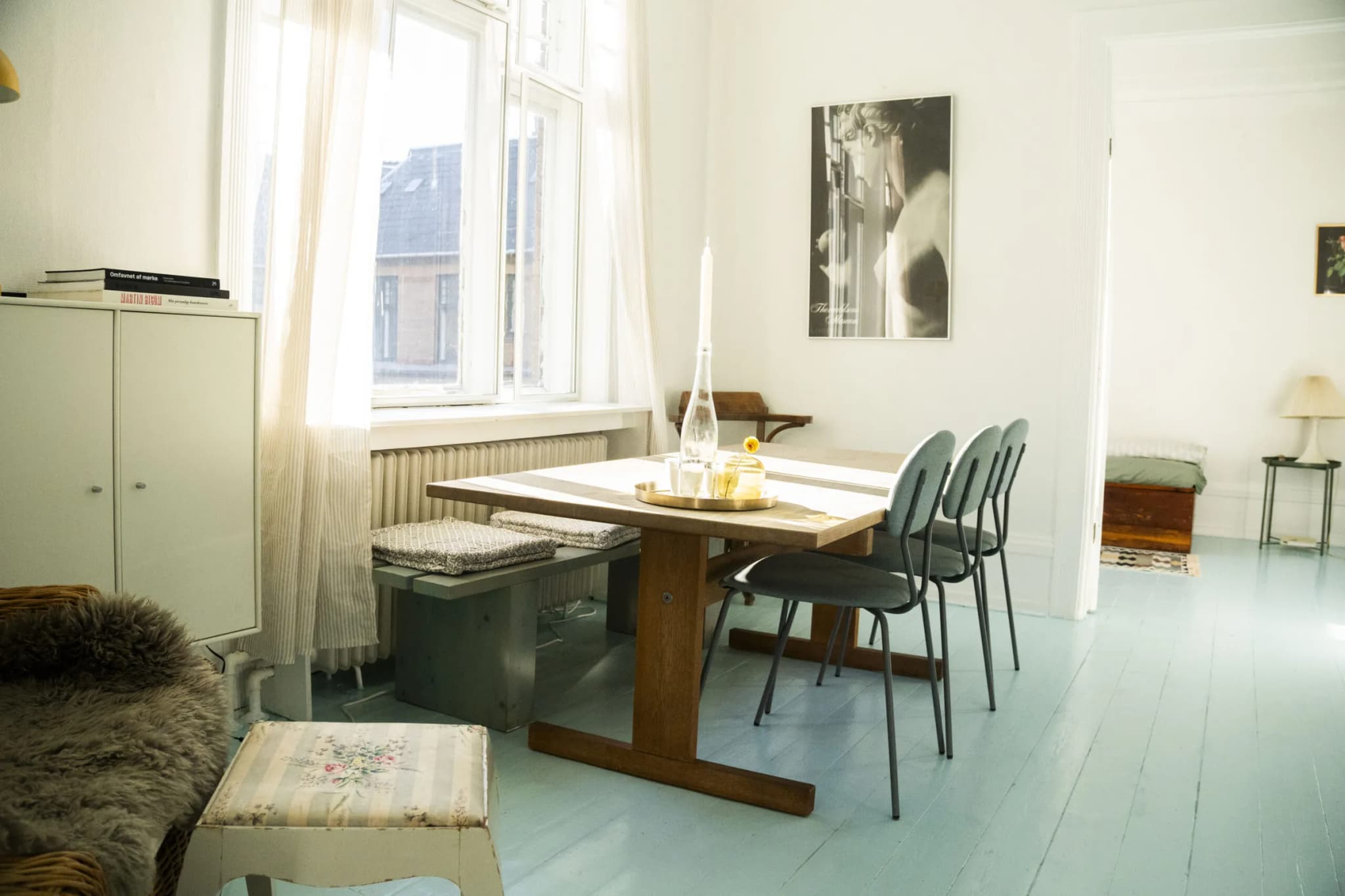 Dining table with green chairs by tall windows in an apartment on Vesterbrogade
