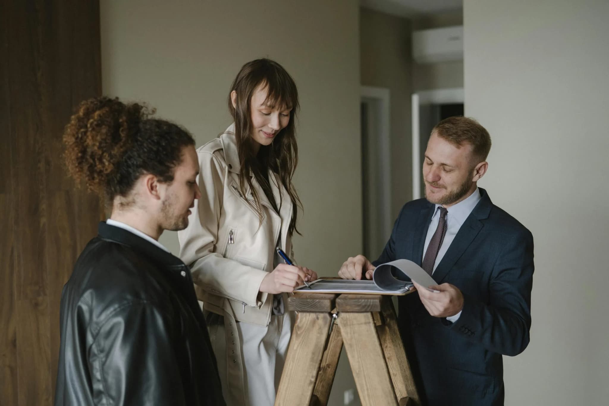 A couple signing property documents with an estate agent in a new apartment