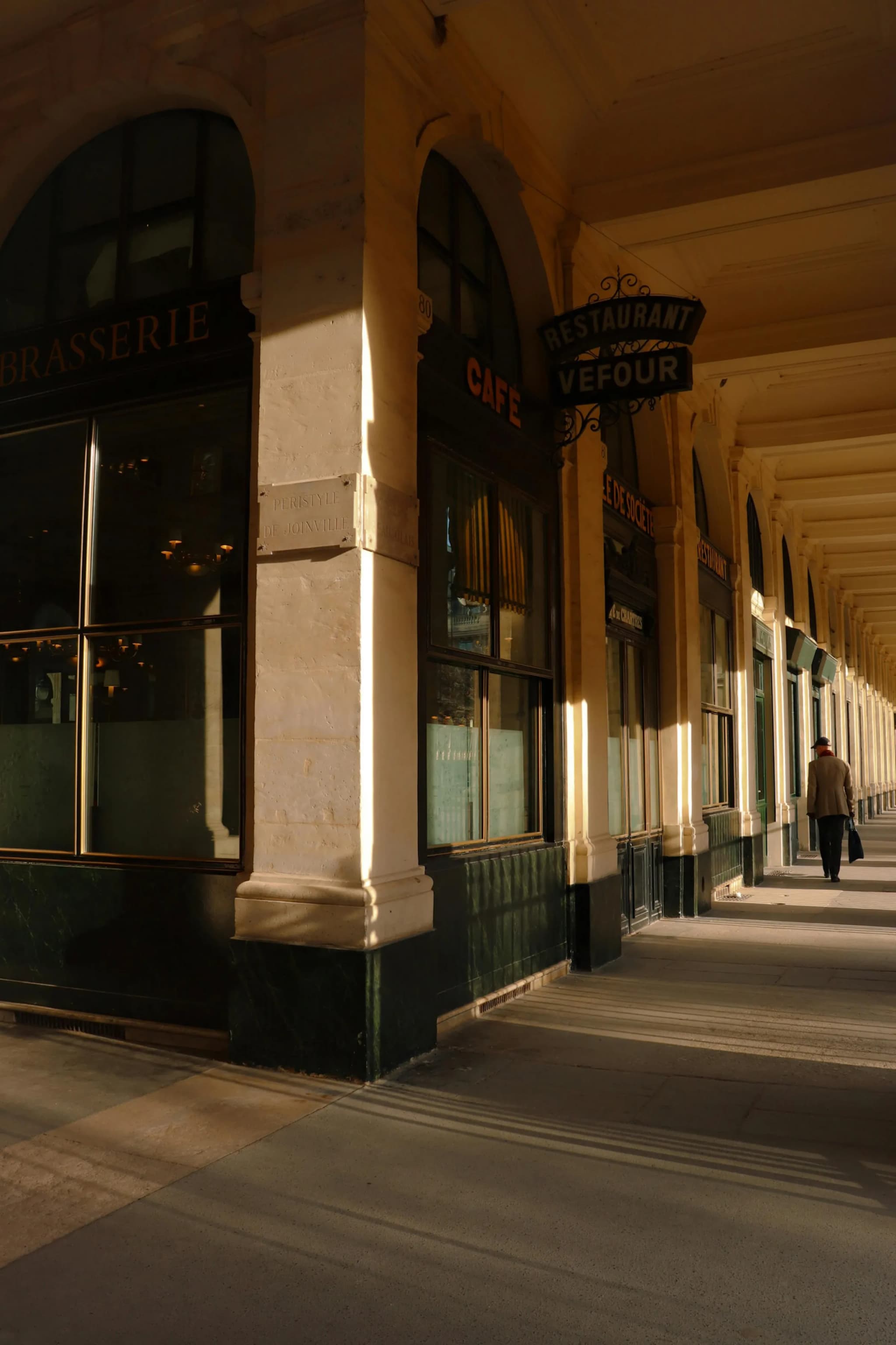 Sunlit corridor of Paris’ Palais Royal highlighting classic architecture.