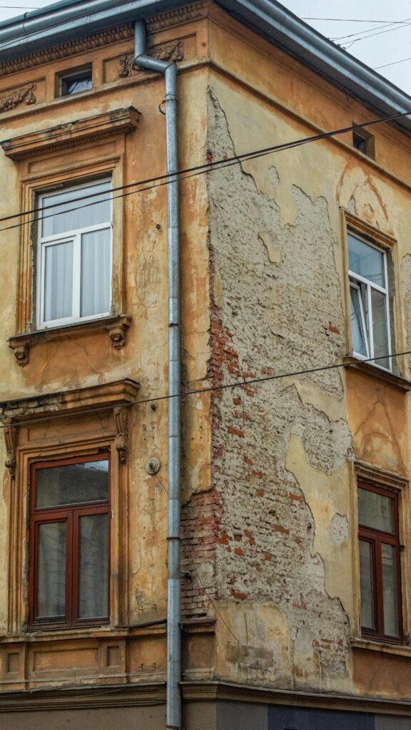 Detailed shot of an old urban building's corner with weathered textures and visible decay.
